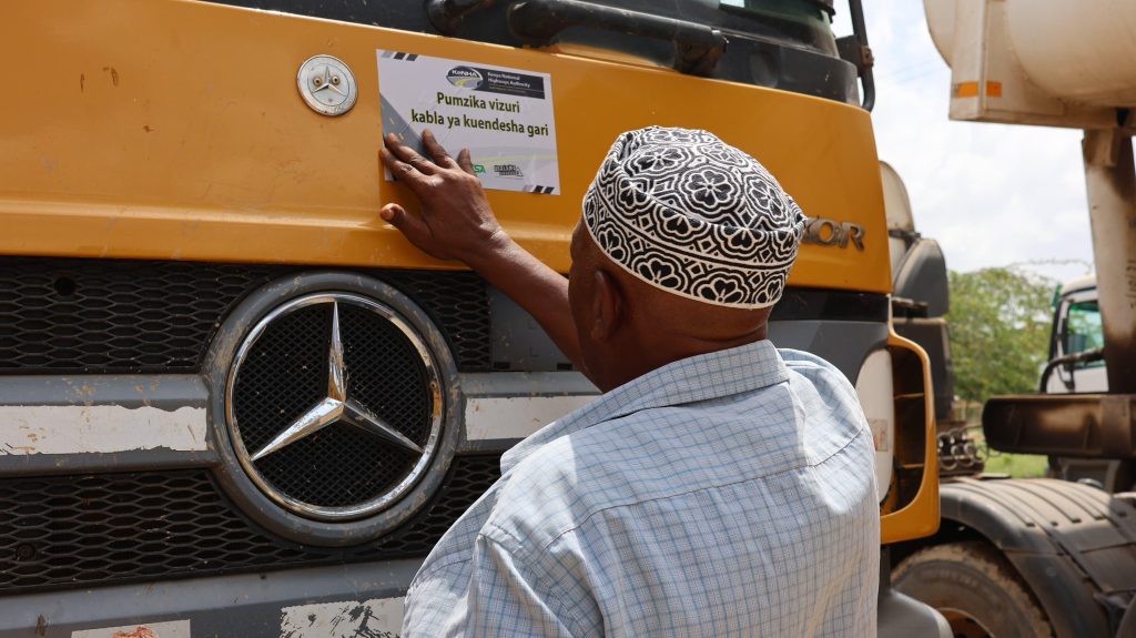 A man places a sticker on a long-distance truck during the sensitization exercise on December 17, 2024. PHOTO/@KeNHAKenya/X