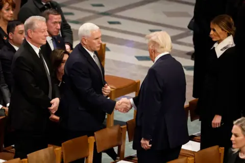 Getty Images Donald Trump and his former Vice-President Mike Pence shake hands at Jimmy Carter's funeral service.