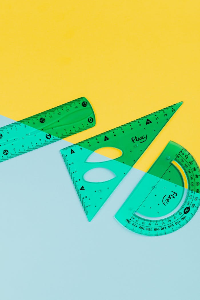 Top view of colorful rulers and protractors on a pastel yellow and blue background.